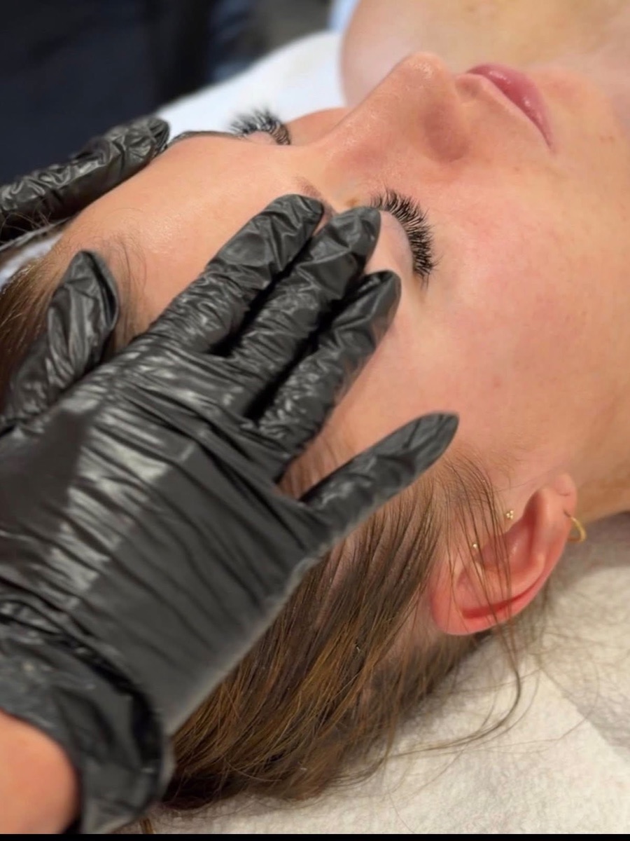 Queenie performing a facial lymphatic drainage treatment on a client
