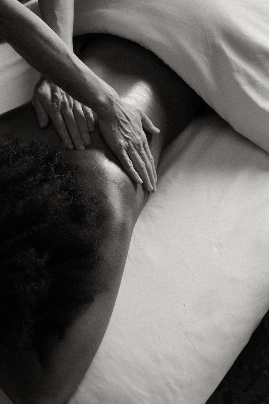 A practitioner's hands working across a client's back in low light
